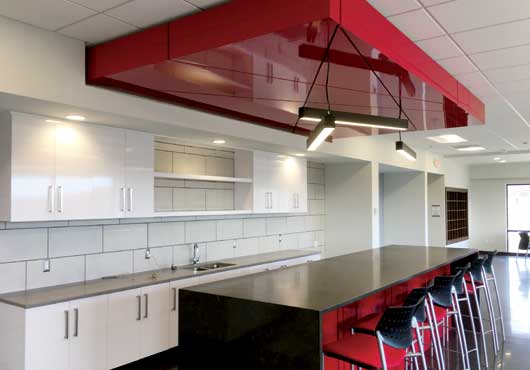 Woodtronics Millwork Corp. created this lunchroom at the offices of food distributor Ace Endico in Brewster, New York. It features custom cabinets, shelving and a plastic laminated ceiling.